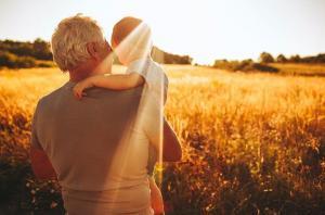 grandfather and child facing away in wheat field