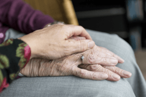 hand holding elderly hands with wedding ring